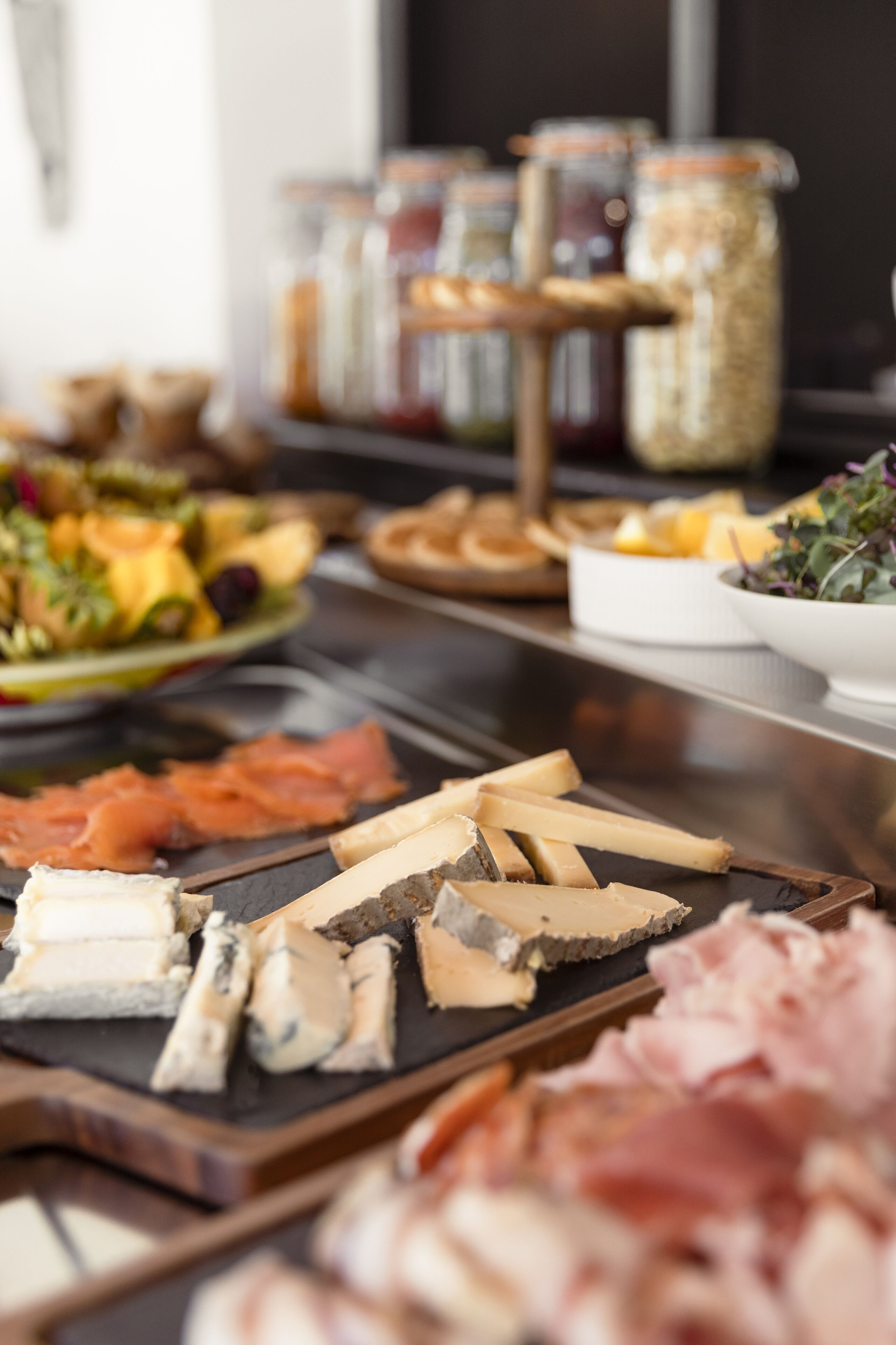 A charcuterie board with various cheeses, meats, and a salad.