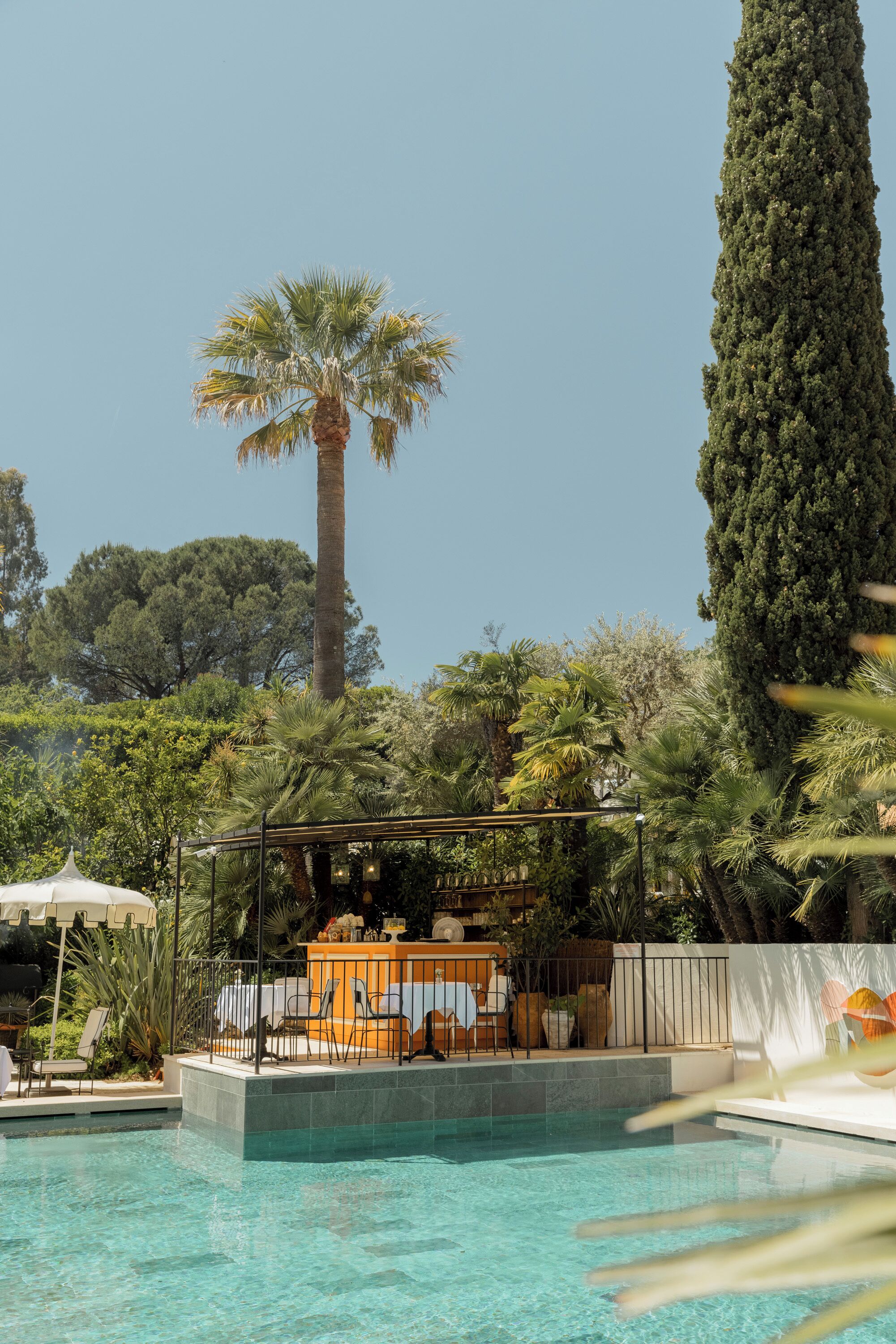 A pool area with a sunbed, lounge chairs, and a pergola.