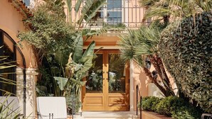 A building with a tiled roof, a wooden door, and a staircase leading to a balcony. - La Bastide de Saint Tropez (Saint-Tropez)