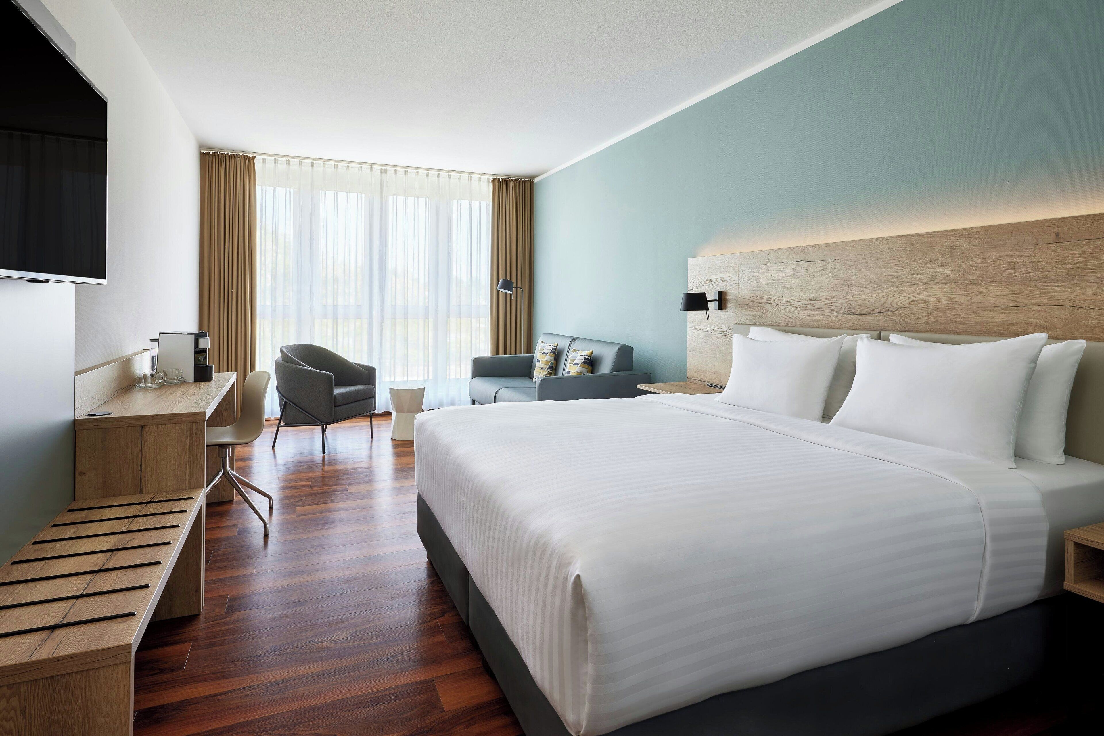Una camera d'albergo con un letto grande, una scrivania, una sedia e una TV.