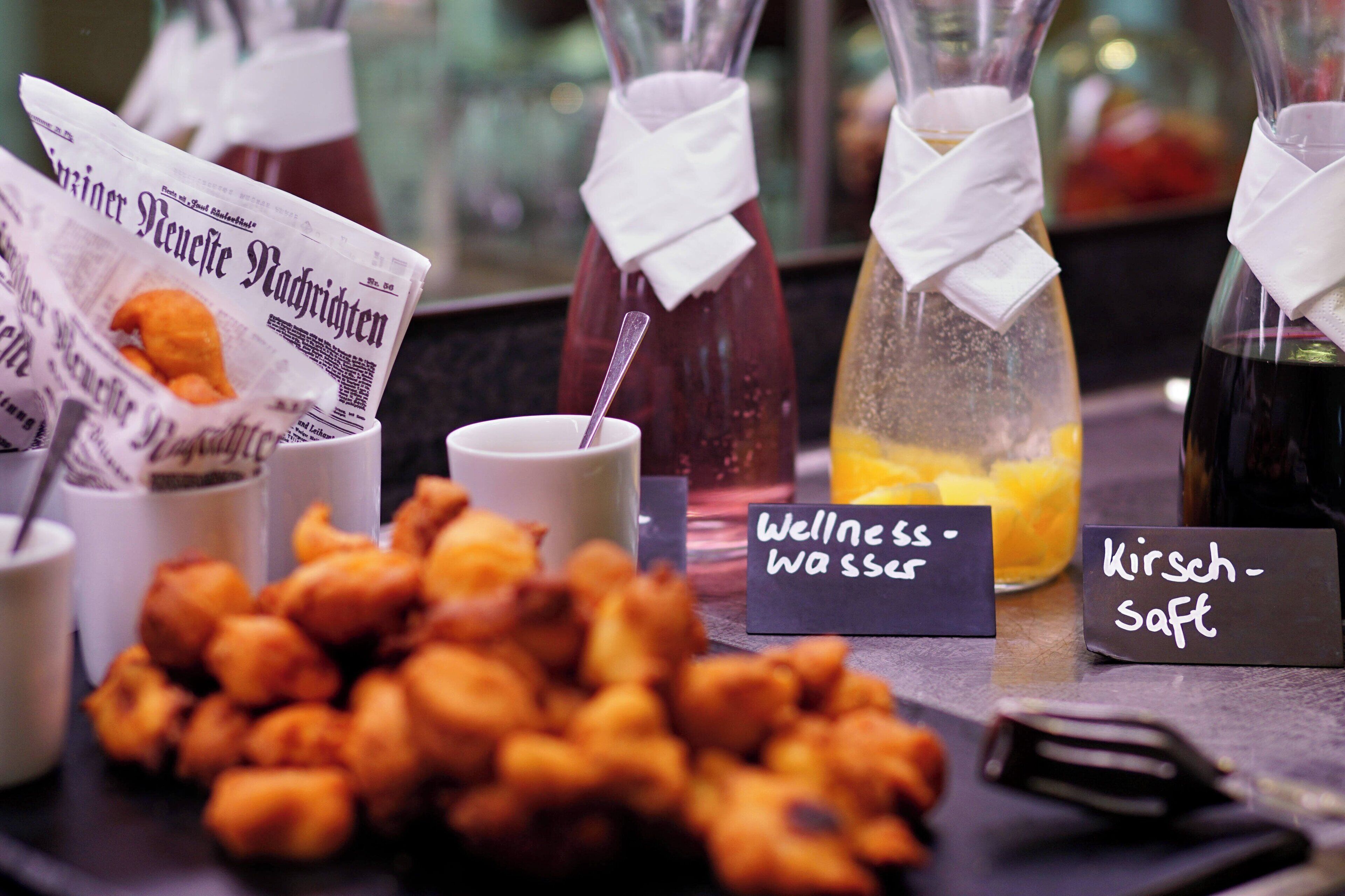 A table with various food items, including fried snacks and drinks labeled 'Wellness water' and 'Kirschtart'.