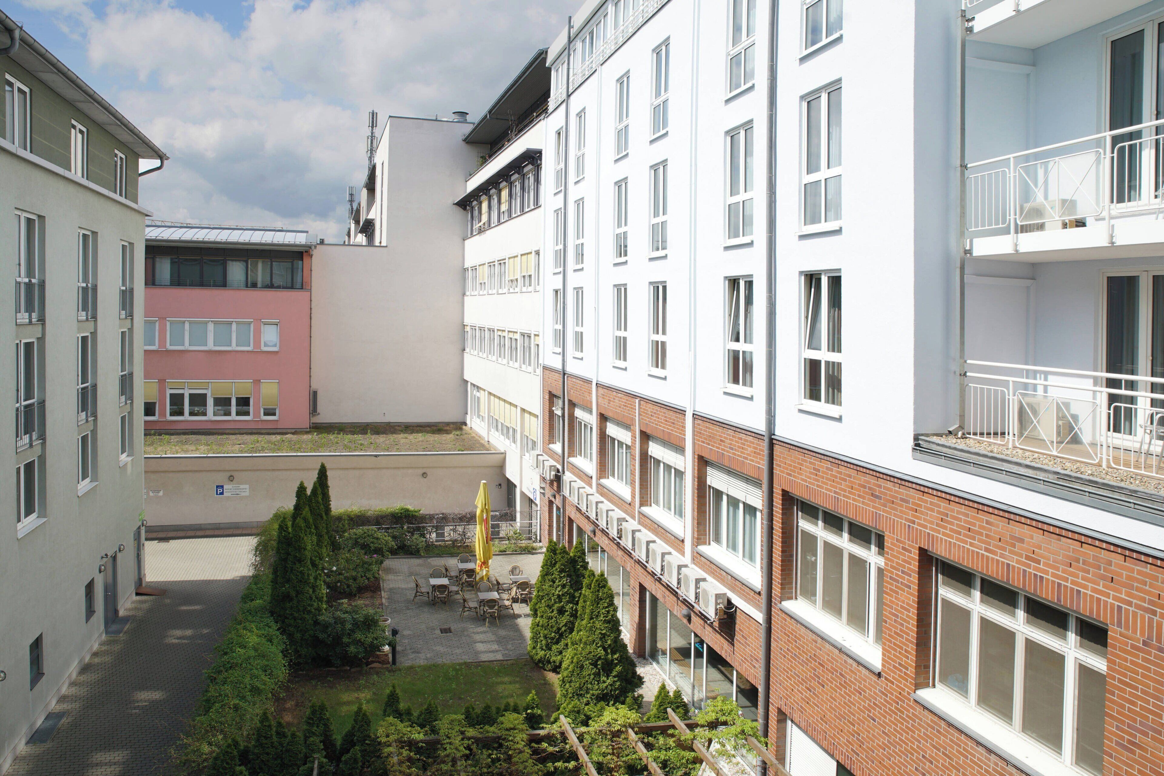 A multi-story building with a courtyard featuring outdoor seating and greenery.