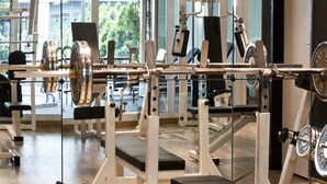 A gym with various exercise machines, a bench press, and a mirrored wall. - Courtyard by Marriott Dresden (Dresden)