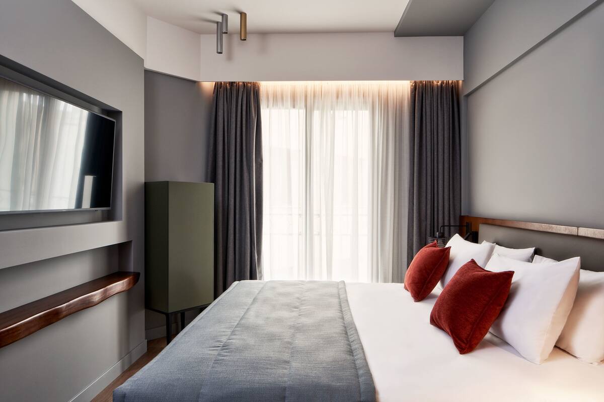 Moderni hotellihuone, jossa on suuri sänky, taulutelevisio ja vaatekaappi.