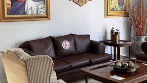 A living room with a brown leather sofa, striped armchair, and a coffee table with decorative items. - La Quinta Hotel (La Ceiba)