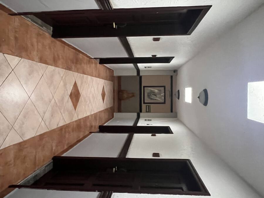 A hallway with a tiled floor, a framed picture on the wall, and a light fixture.