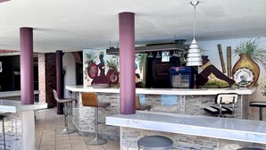 An outdoor bar area with high stools, a counter, and a mural on the wall. - La Quinta Hotel (La Ceiba)