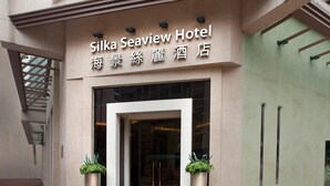 The exterior of Silka Seaview Hotel with a prominent sign, entrance, and two potted plants at the entrance. - Silka Seaview (Kowloon)