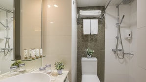 A modern bathroom with a large bathtub, a toilet, and a shower. There are toiletries on the counter and a small plant on the sink. - Silka Seaview (Kowloon)