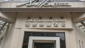 The Silka Seaview Hotel entrance with a modern design, featuring a large glass door and two potted plants on either side. - Silka Seaview (Kowloon)
