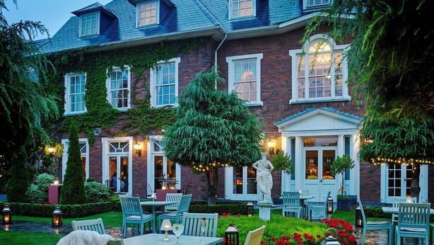 A brick house with ivy-covered walls, outdoor seating, and a statue. - Hayfield Manor (Cork)