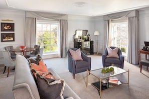 A spacious living room with a sofa, two armchairs, a coffee table, and a fireplace.