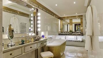 A luxurious bathroom with a large vanity, a freestanding bathtub, and multiple mirrors with lights.