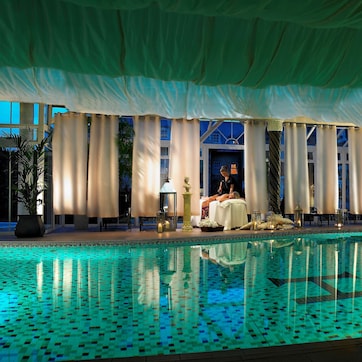 A pool area with a massage chair, a statue, and a potted plant.