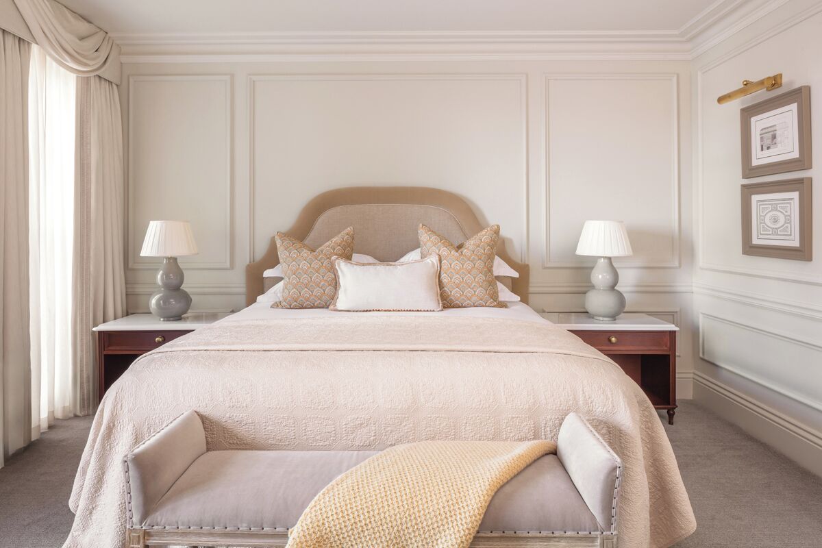 Une chambre bien rangée, avec un grand lit, deux tables de chevet et une chaise.