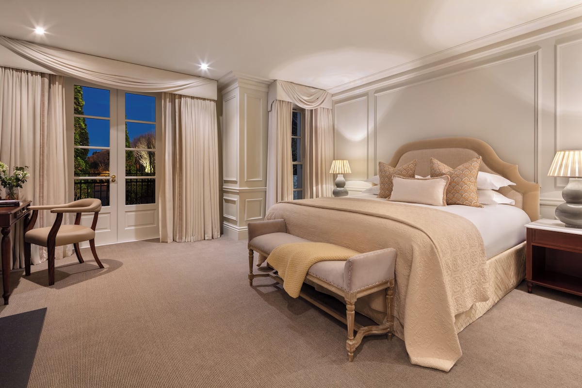 A spacious bedroom with a large bed, a sitting area, and a view of the outdoors.