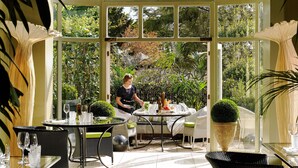 A conservatory with a chef preparing food, dining tables, and chairs. - Hayfield Manor (Cork)