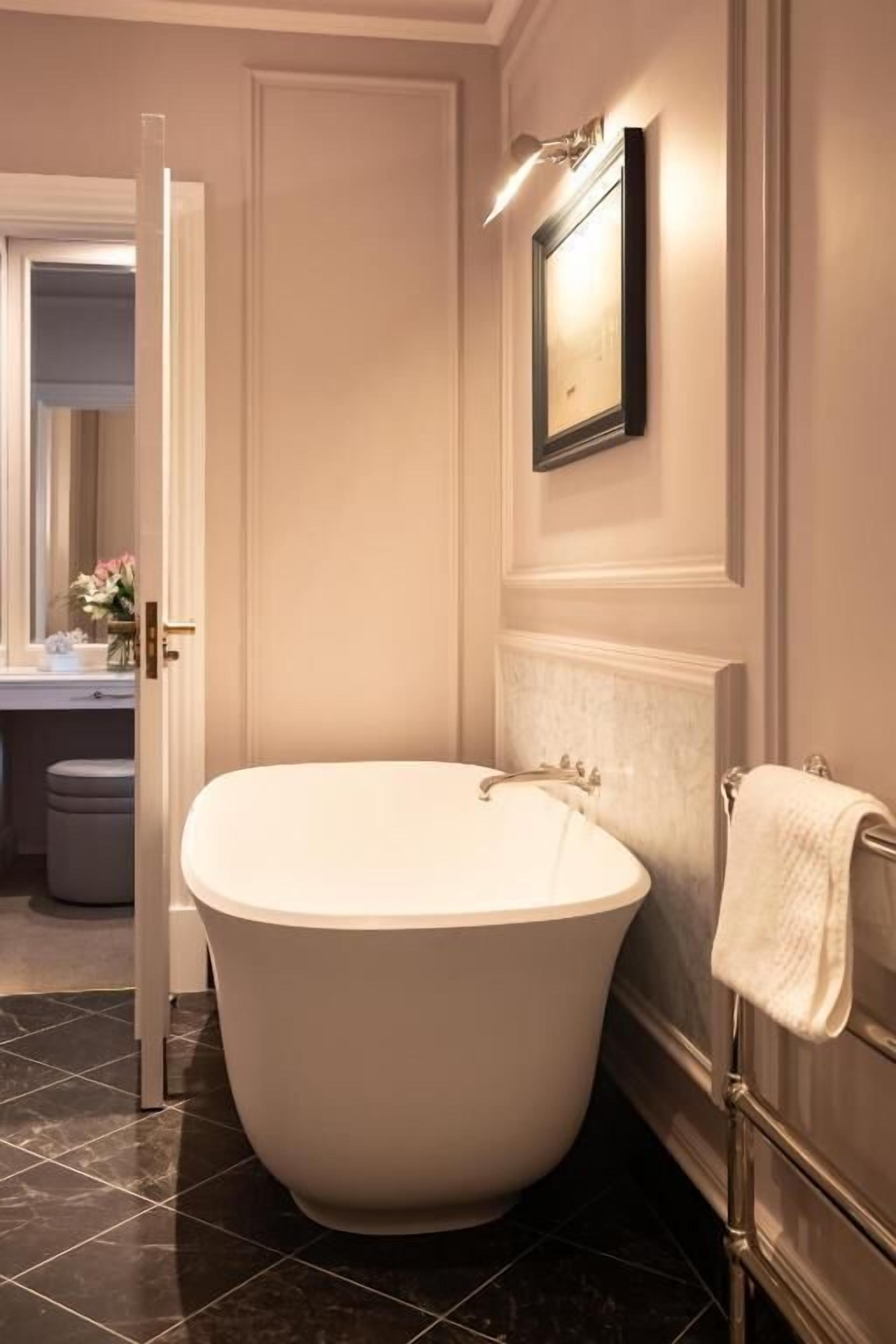 A bathroom with a freestanding bathtub, a towel rack, and a framed picture on the wall.