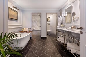 A modern bathroom with a freestanding bathtub, a vanity with a large mirror, and a shower area.