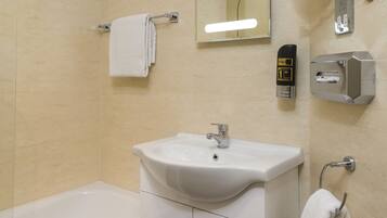 A bathroom with a white sink, a mirror, a hand dryer, and a towel rack.