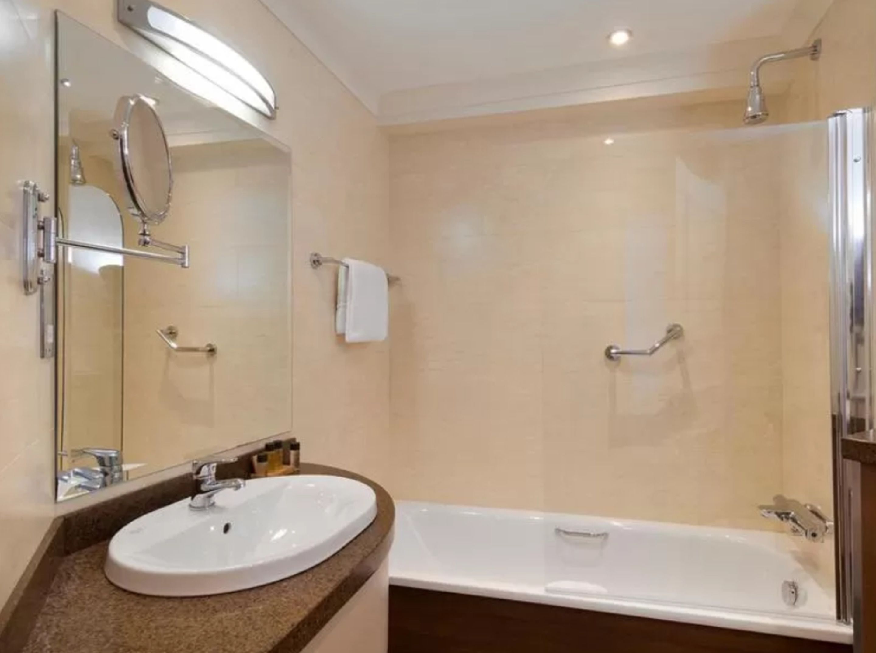Un baño moderno con un lavamanos grande, espejo y ducha.