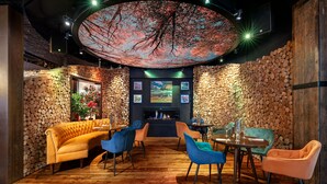 Un restaurant acollidor amb sostre de fusta, una llar de foc i una paret de pedra.