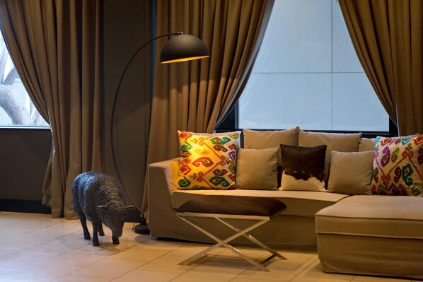 A living room with a sofa, colorful pillows, a lamp, and a small animal figurine.