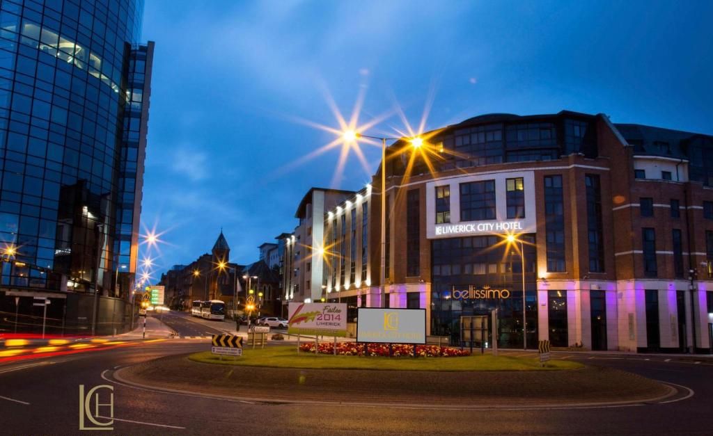 The Limerick City Hotel with a modern glass facade, a prominent 'bellissimo' sign, and a well-lit entrance.