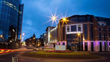 The Limerick City Hotel with a modern glass facade, a prominent 'bellissimo' sign, and a well-lit entrance.
