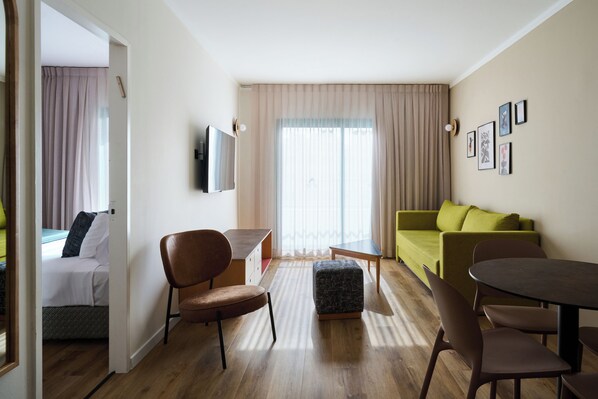 Une chambre d’hôtel moderne équipée d’un lit, d’un bureau, d’un canapé vert et d’une table à manger.