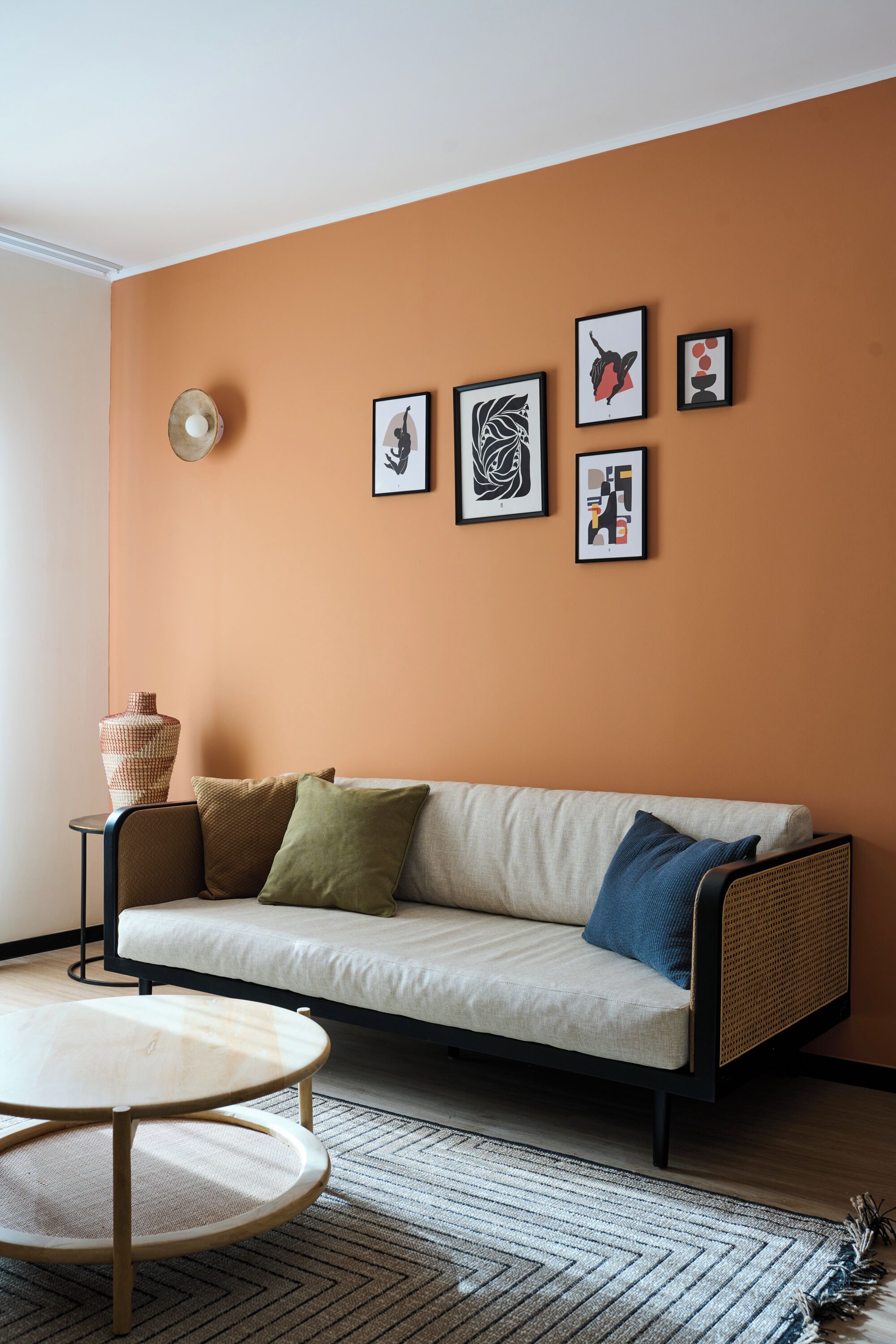 Ein Wohnzimmer mit einer Couch, einem runden Couchtisch und einem Teppich. An den Wänden befinden sich gerahmte Kunstwerke.