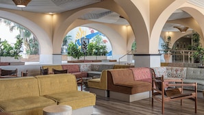 Un amplio salón con techos altos, nichos abovedados y diferentes opciones de asiento, incluyendo sofás y sillones.