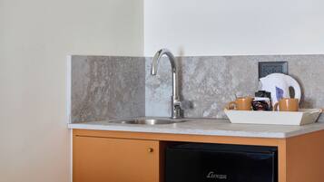 Una cocina compacta con lavavajillas integrado, un lavabo y una encimera con dispensador de café y té.