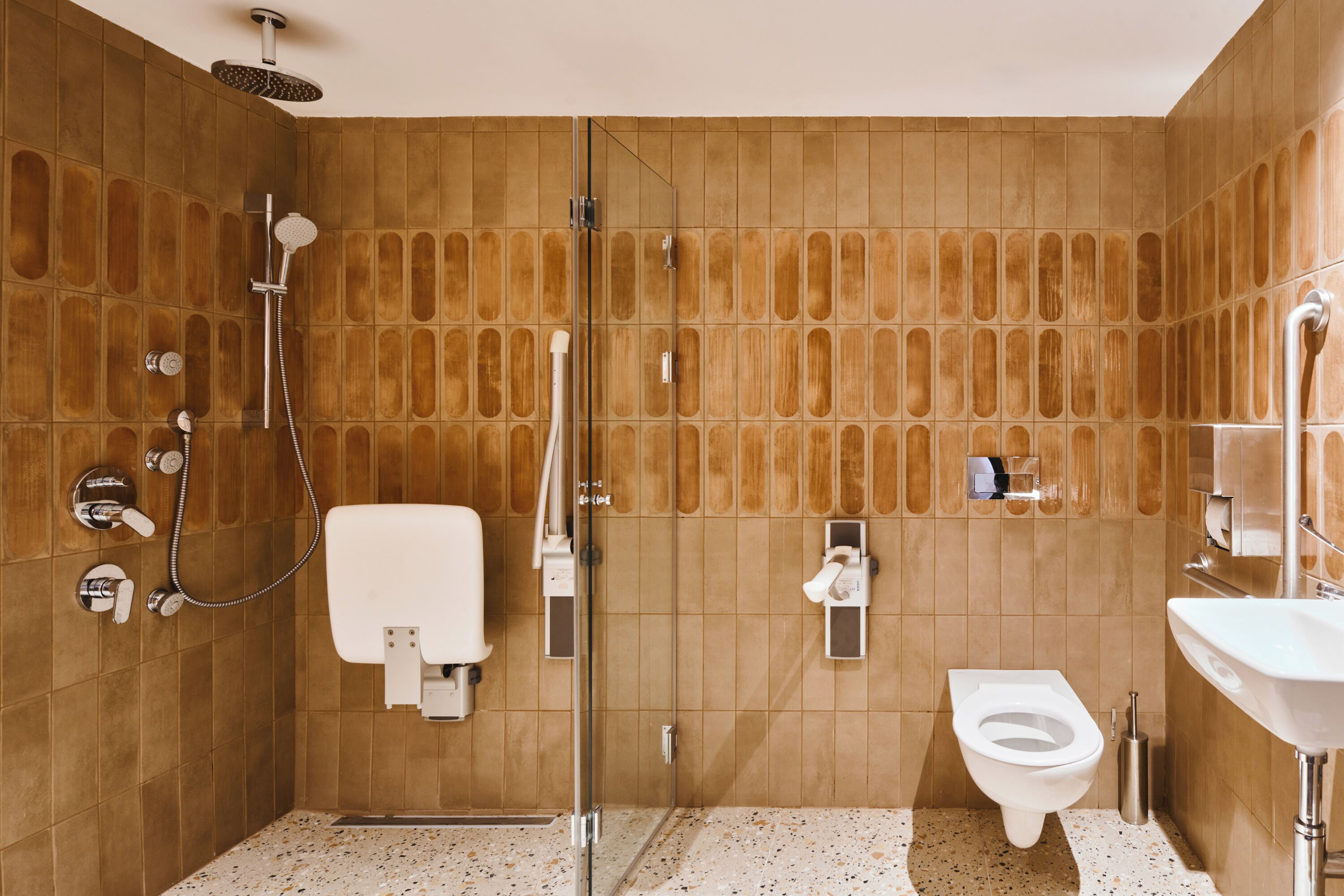 A bathroom with a glass-enclosed shower, a toilet, and a sink.