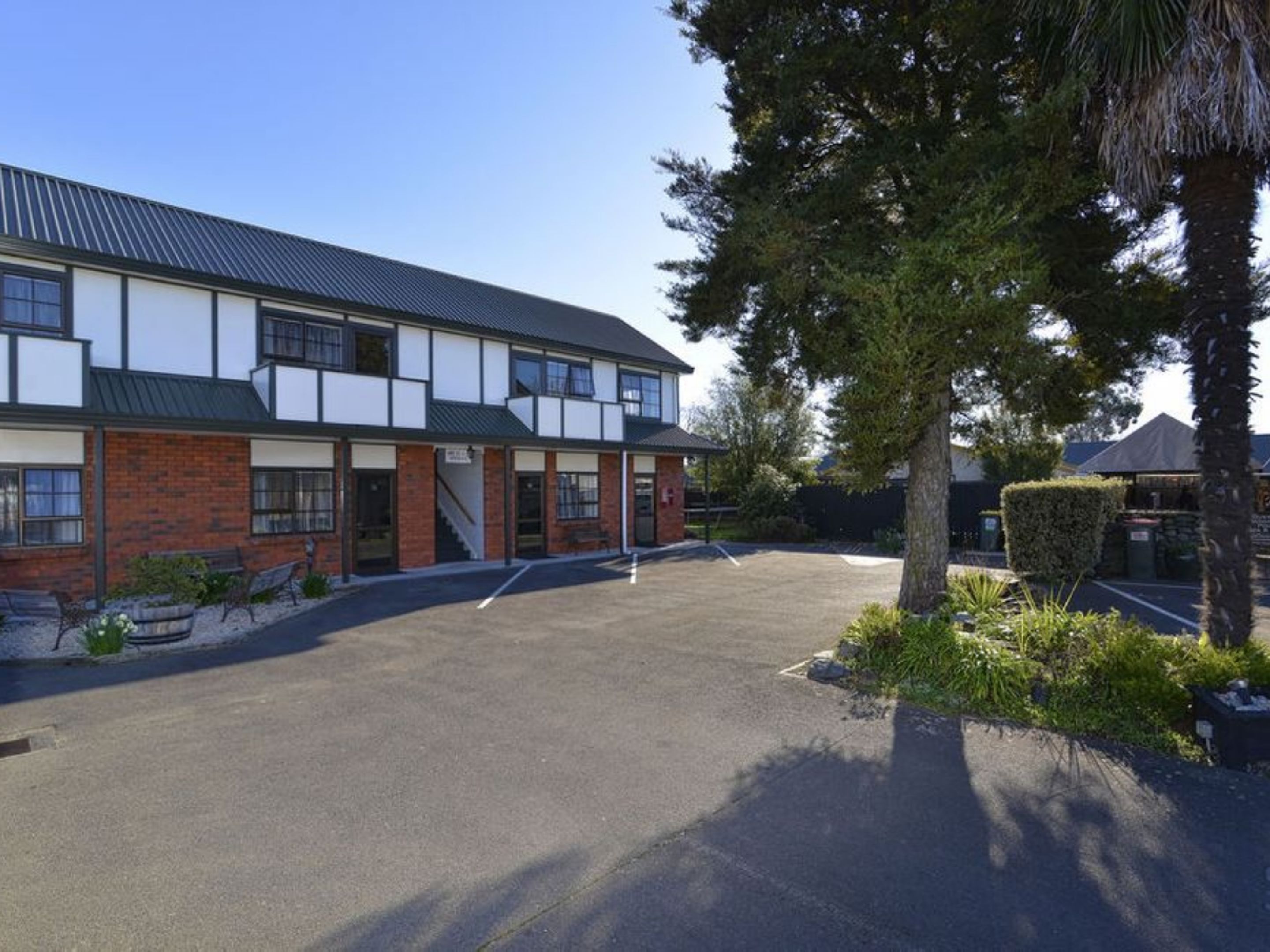 A two-story building with a flat roof, large windows, and a paved driveway.