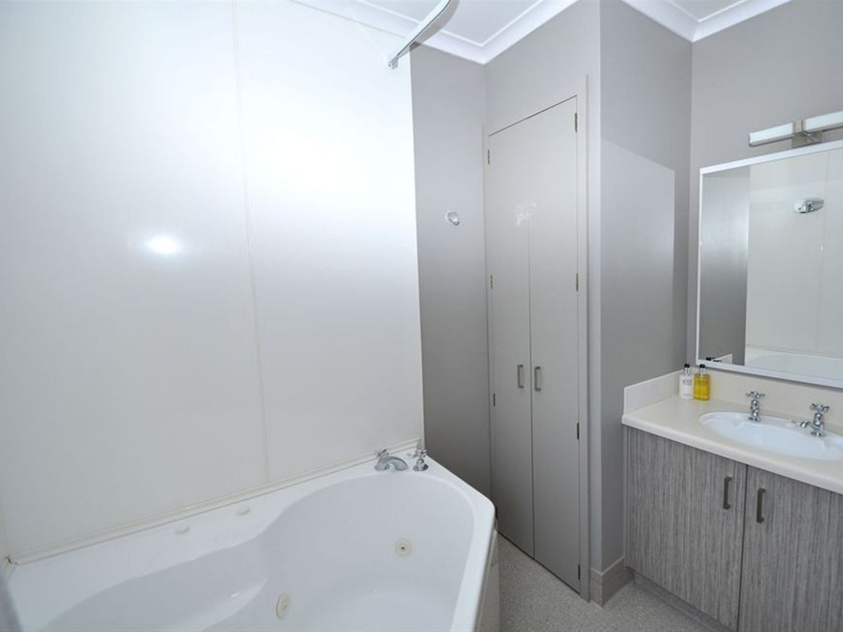 A modern bathroom with a freestanding bathtub, a vanity with a mirror, and a door leading to another room.