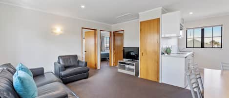 A modern living room with a leather sofa, a TV, and a dining area with a table and chairs.