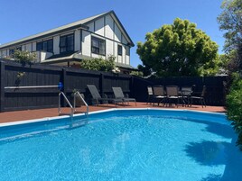 Una piscina al aire libre de temporada, sillones reclinables de piscina