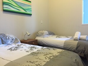 Une chambre avec deux lits, une table de chevet, une lampe et un tableau au mur.