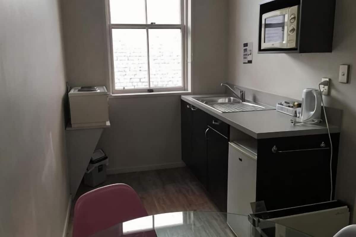 A small kitchenette with a sink, microwave, and cabinets.