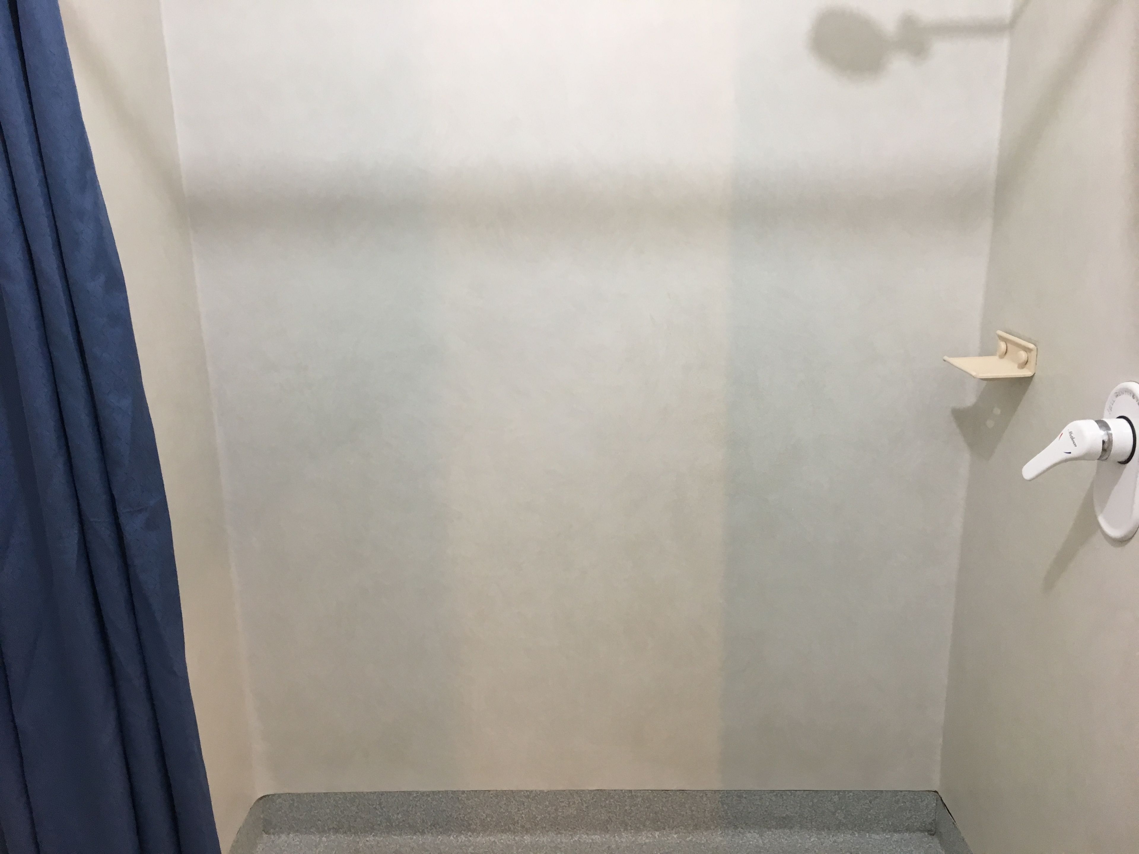 A bathroom with a shower, a towel rack, and a toilet.
