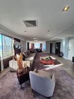 A spacious living area with a sofa, armchairs, a coffee table, and a large window.