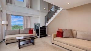 A spacious living room with two sofas, a coffee table, and a staircase leading to an upper level. - Novotel Rotorua Lakeside (Rotorua)