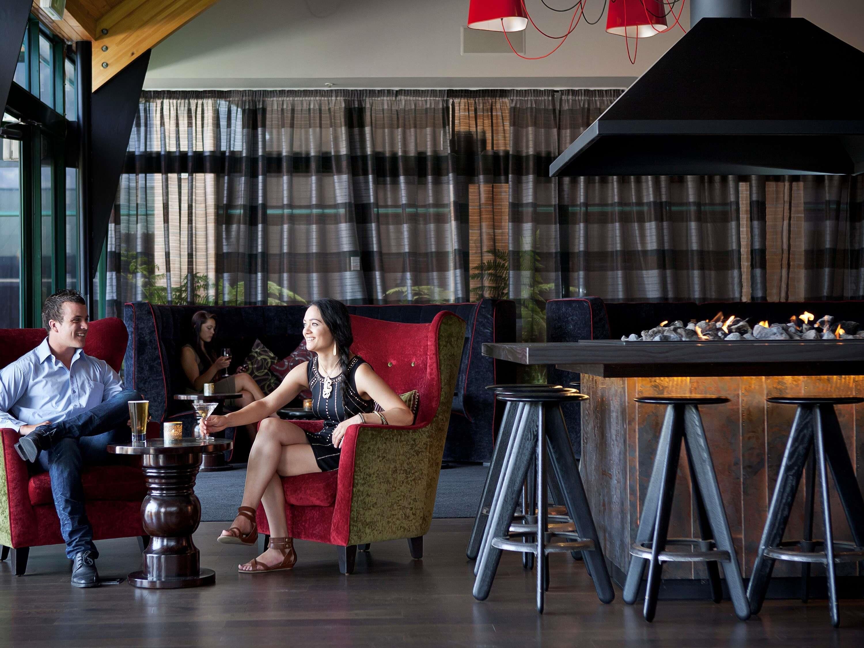 A modern lounge area with seating, a bar, and a fireplace.