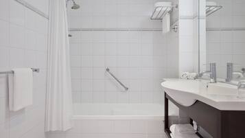 A modern bathroom with a bathtub, shower, and vanity with a mirror.