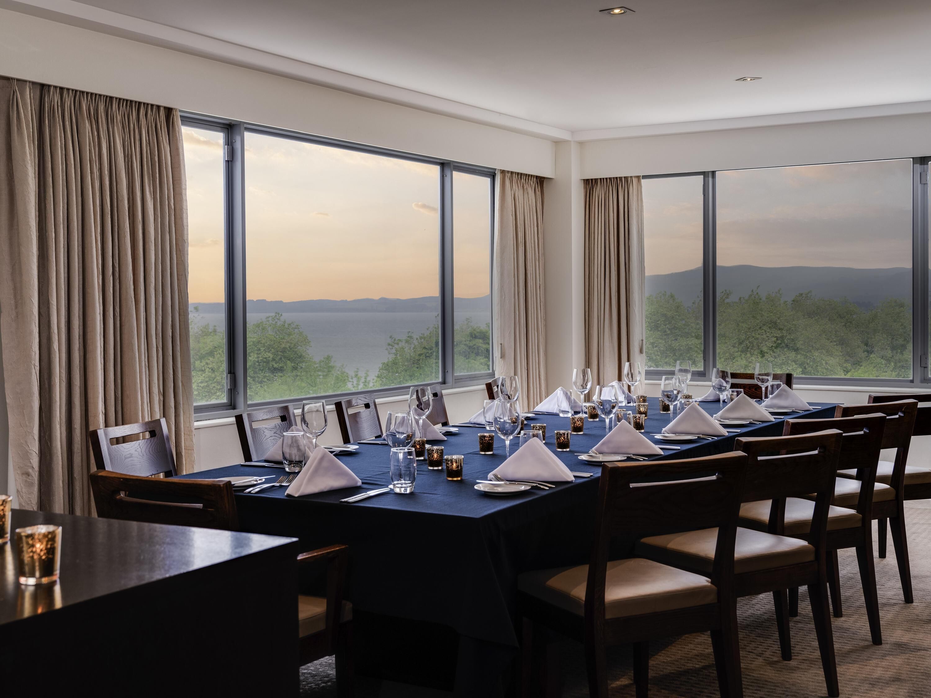 Zona pranzo con tavoli apparecchiati per un pasto, ampie finestre che offrono una vista panoramica sul paesaggio e un design d'interni moderno.