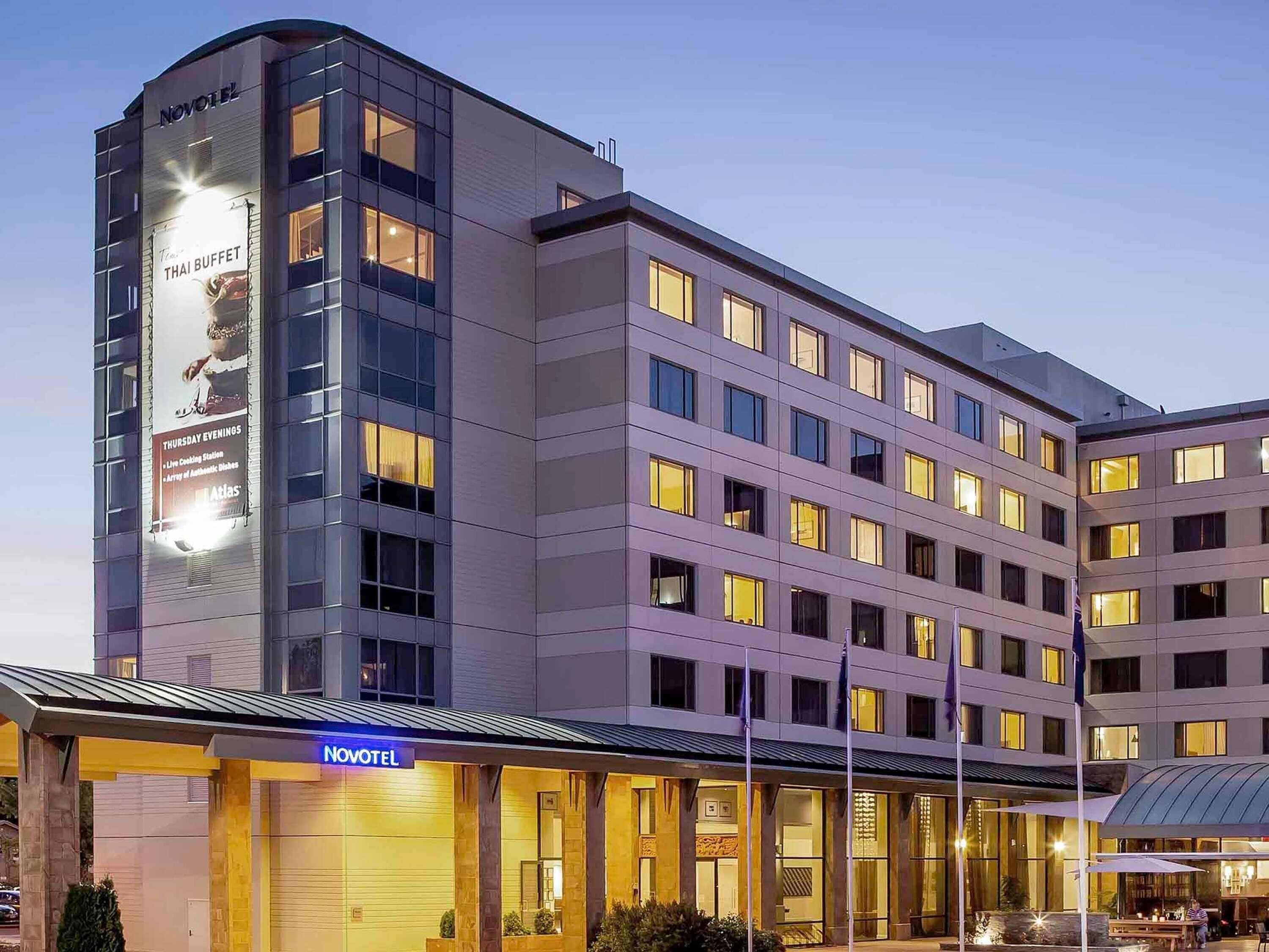 En modern hotellbyggnad med en tydlig skylt som visar varumärket ”Novotel”, flera våningar och en väl upplyst entré.