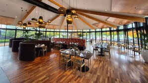 A spacious indoor area with wooden floors, large windows, and multiple seating arrangements. - Novotel Rotorua Lakeside (Rotorua)