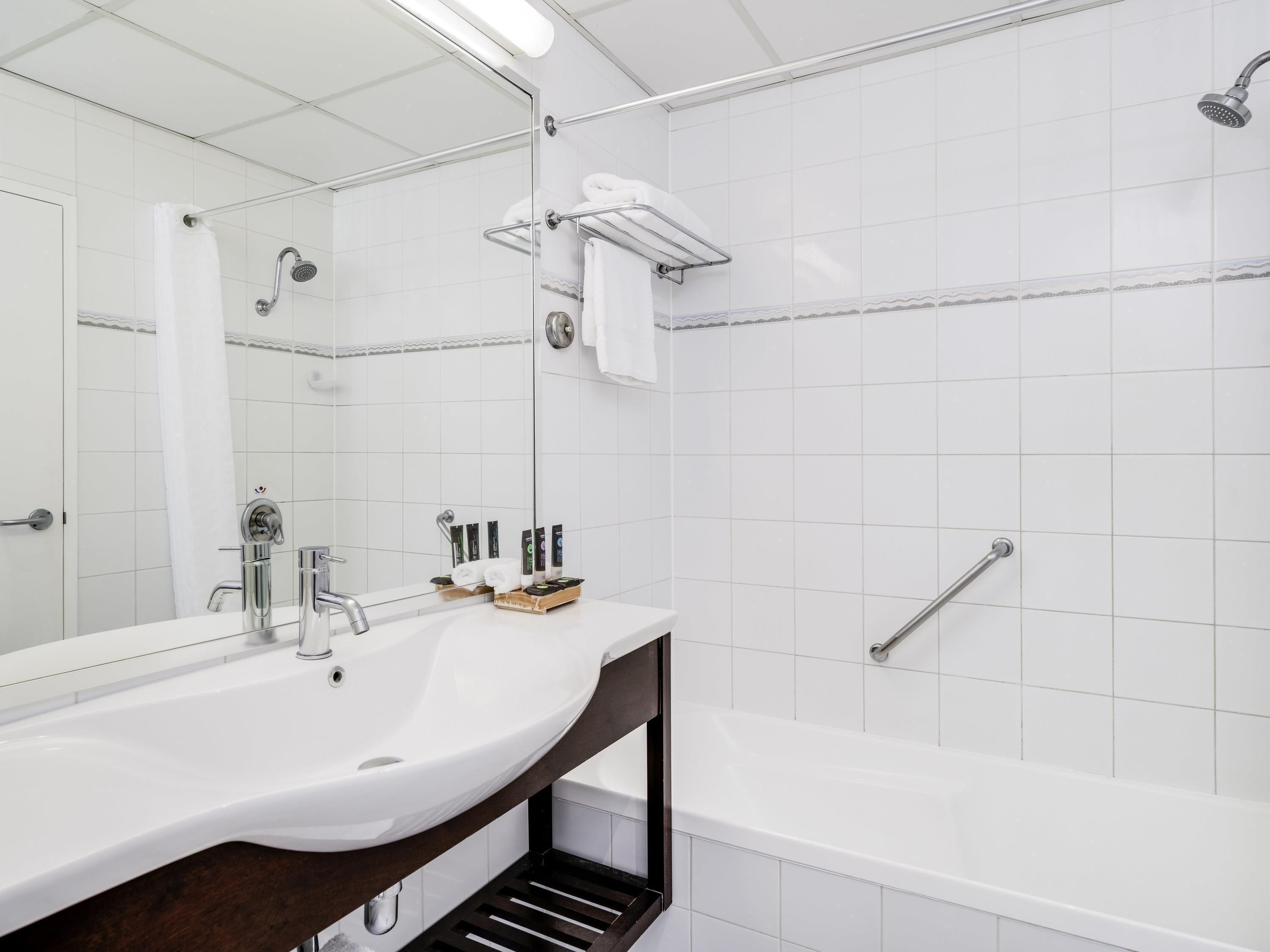 A modern bathroom with a white sink, a mirror, a shower, and a bathtub.