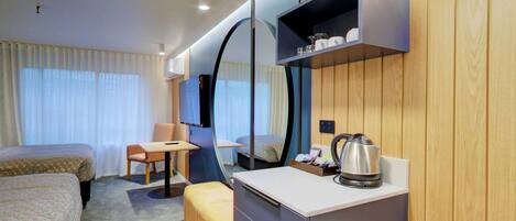 A hotel room with two beds, a desk, a chair, a television, and a coffee maker.